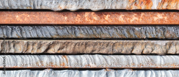 Fototapeta Stack of  thick heavy metal plates rusty uneven surface after laser cutting. plates stacked top each other, creating sense depth and texture. scene is somewhat dark industrial  background