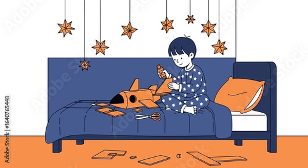 Fototapeta Enthusiastic young boy in star pajamas creates a cardboard rocket on his bed in his room