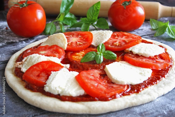 Obraz Raw Caprese pizza with tomato, mozzarella and basil leaves. Selective focus
