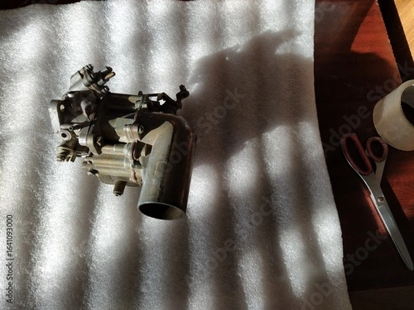 Fototapeta Old carburetor for a car engine with tools on table