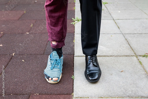 Fototapeta Poor vs rich person. A wealthy business man in a suit against a homeless with ragged clothes. Different pants and shoes. Contrast in the society and class struggle. Failure versus success concept.