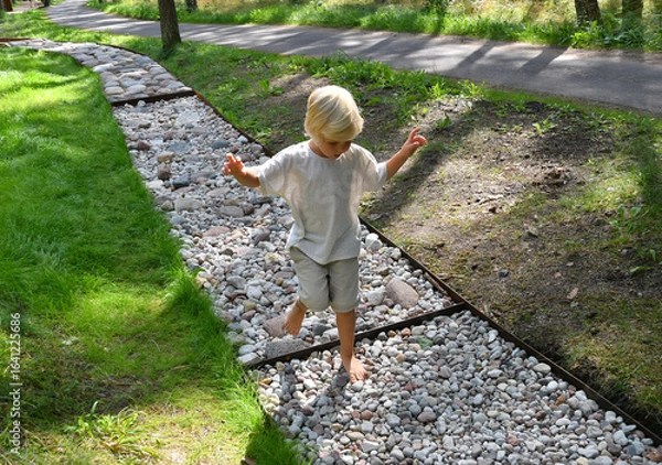 Fototapeta Barefoot boy walking on a sensory trail through a pine forest in Lithuania