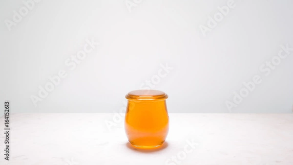 Fototapeta Honey - a jar filled to the brim, just one drop before overflowing.  Life is full and sweet!
