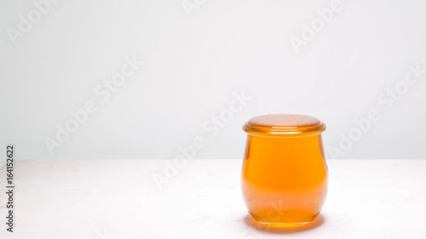 Fototapeta Perfectly full jar of honey with copy space to the left.  Life is full and sweet!