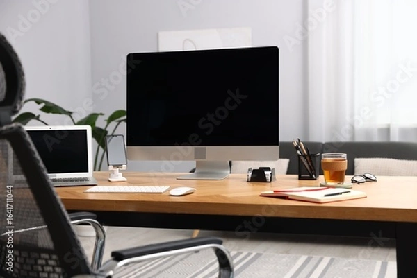 Fototapeta Stylish workplace with modern computer, other devices and stationery on wooden desk indoors