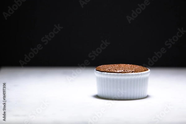 Fototapeta Chocolate creme brulee before caramelization, in a ramekin on white marble against a black background