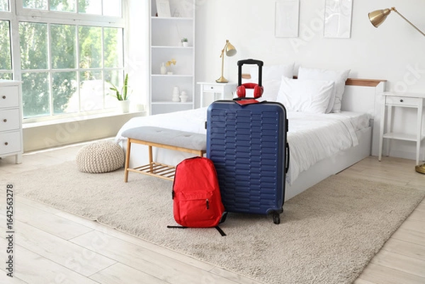 Fototapeta Bags with headphones and passport on carpet in hotel room interior