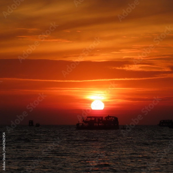 Fototapeta bright red sunset with shadows of boats in the water