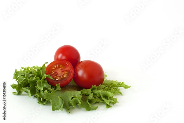 Obraz Several cherry tomatoes on fresh lettuce leaves on a white background
