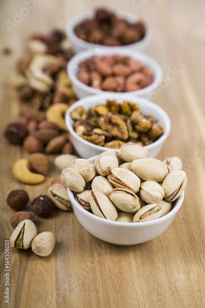 Obraz Four bowls with nuts on a  wooden table.