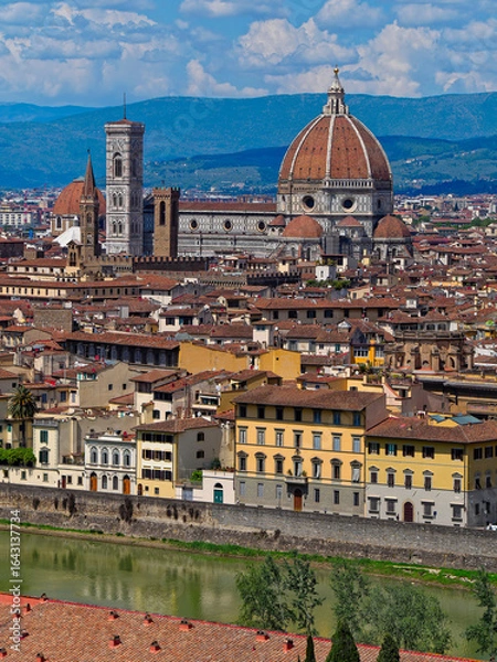 Fototapeta Arno River flows in the foreground, while the dome of Santa Maria del Fiore dominates the skyline, with the Church of San Lorenzo nestled in the background, adding depth to Florence’s  grandeur.