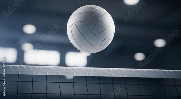 Fototapeta A volleyball hovering over a net in a dimly lit gymnasium with blurred lights in the background