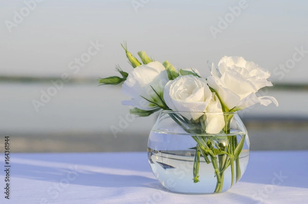 Obraz White roses in a vase on the beach