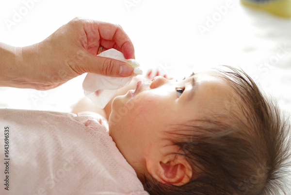 Fototapeta 優しく赤ちゃんの顔を拭くママの手元