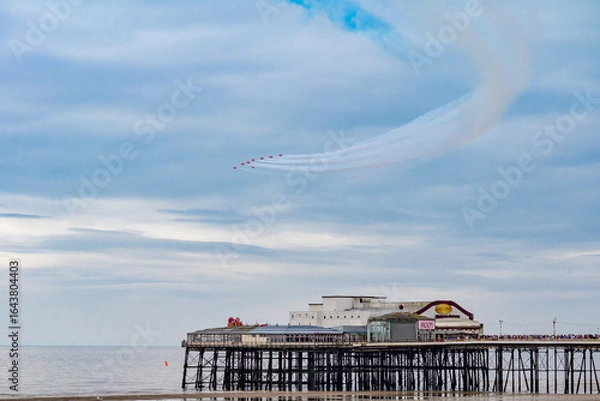 Obraz Blackpool, England - 10th August 2025: The Red Arrows performing an aerial display using red, white and blue smoke over the North Pier as part of the Blackpool Air Show