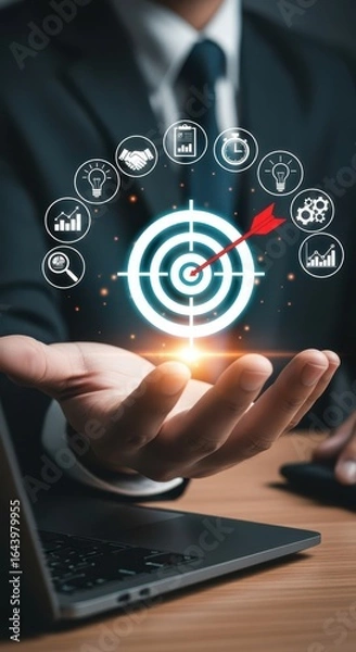 Fototapeta Businessman holding holographic target with arrow in bullseye, surrounded by business icons, representing strategy, goals, and success.