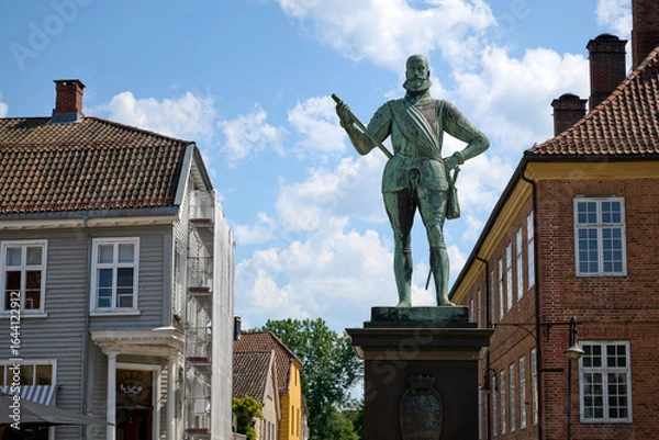 Obraz Bronze Statue in Historic Gamlebyen Frederikstad Surrounded by Traditional Scandinavian Architecture Under a Bright Summer Sky