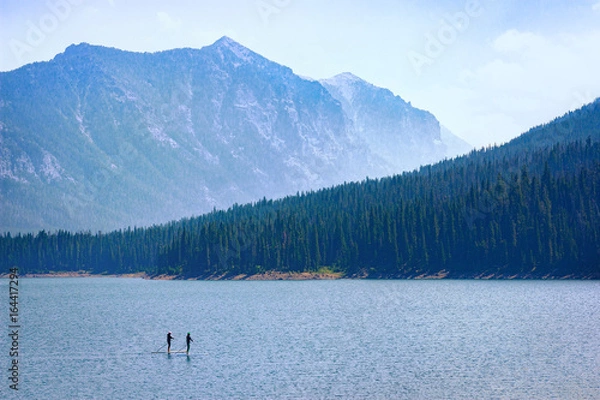 Fototapeta Mountain Lake Recreation. Paddle boarders drift through the Hyalite Reservoir in Montana. Majestic copy space.