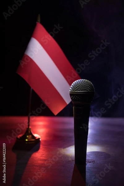 Fototapeta Microphone on a background of a blurry flag of Austria close-up. dark table decoration