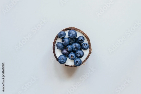 Fototapeta Ripe coconut with blueberry on the gray background, top view