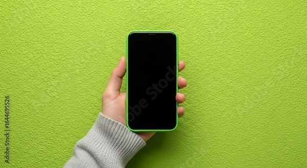 Fototapeta Hand holding modern smartphone with blank screen on textured green background