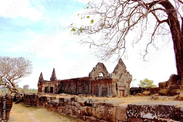 Obraz Ancient stone temple ruins of Wat Phou in Champasak, Laos, with a bare tree under a bright sky.