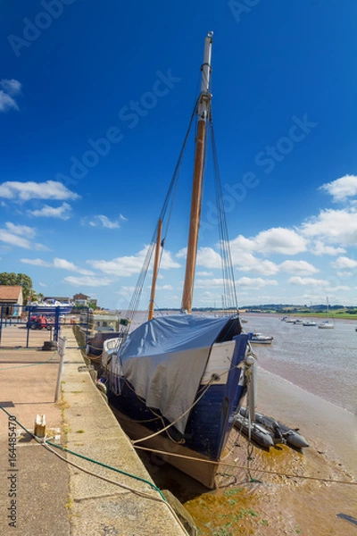 Fototapeta An old ship with a mast. Covered with tarpaulin. Moored at the shore at low tide. Topsham. Devon. England