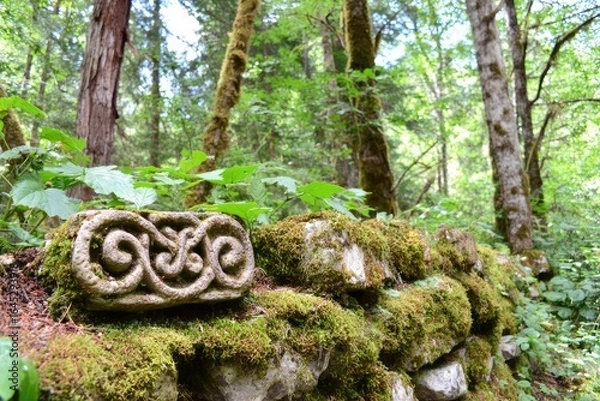 Fototapeta Ornate stone fragment in mossy forest