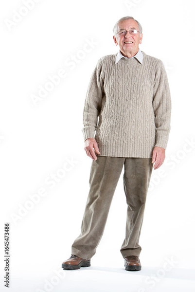 Fototapeta Elderly man in a knitted jumper. A senior man stands looking at the camera with a neutral expression.