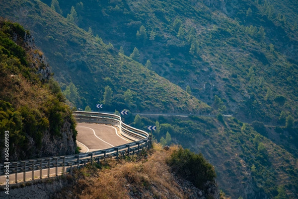 Fototapeta Winding mountain road with guard rails and directional signs