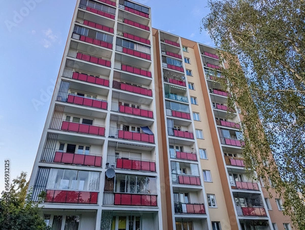 Fototapeta Warsaw, Poland, June 16, 2025, Modern residential apartment building with colorful balconies and contemporary architecture under bright blue summer sky in urban setting