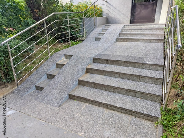 Fototapeta Modern concrete stairs with horizontal metal handrails leading upward in contemporary architectural setting