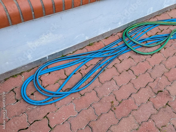 Fototapeta Colorful fiber optic cables coiled on red brick paving stones showing telecommunications infrastructure installation work