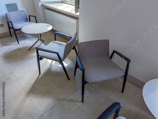 Fototapeta Contemporary office chairs with metal frames positioned on polished concrete floor in modern workspace environment