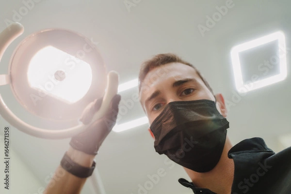 Obraz The dentist looks at the camera and shines a lamp.