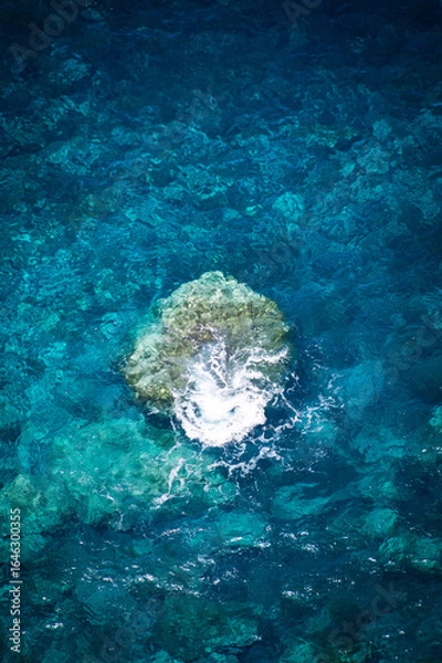Fototapeta Wave Crashing Over Submerged Rock in Clear Blue Ocean