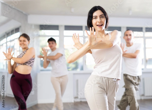 Fototapeta Group of young people, girls and guys in sportive casual style clothes dancing in choreography class