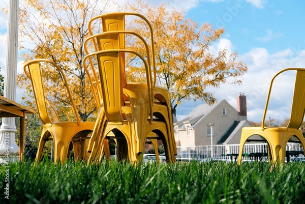 Fototapeta Yellow chairs stacked on a green lawn