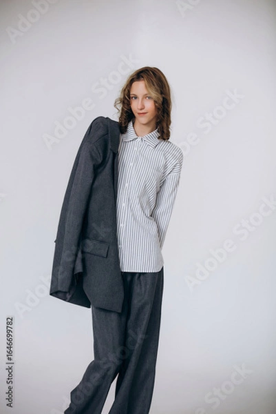 Fototapeta A teenage girl model is young and beautiful in a business suit and shirt in a studio on a white background