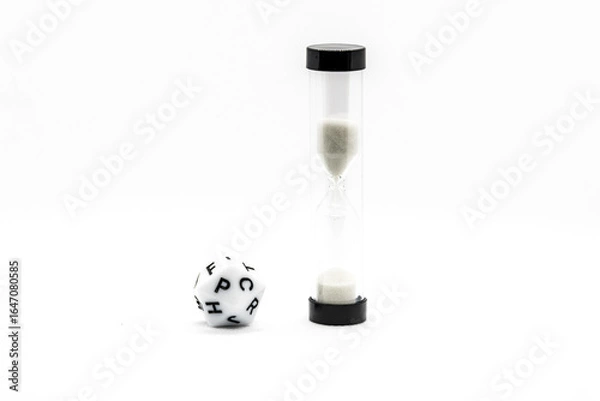 Fototapeta Close-up of an hourglass and letter dice used in board games, isolated on a white background, representing time, word challenges, and educational play.