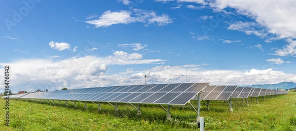 Obraz Panele elektrowni słonecznej pod błękitnym niebem z białymi chmurami - koncepcja czystej energii