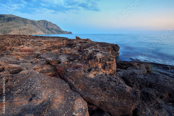 Fototapeta Beautiful mysterious marine landscape at sunset. Volcanic reef and ocean