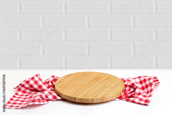 Obraz Round cutting board with checkered kitchen towel on white table