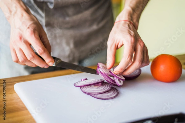 Obraz Hands cutting onion and radish for fresh vegetable salad.