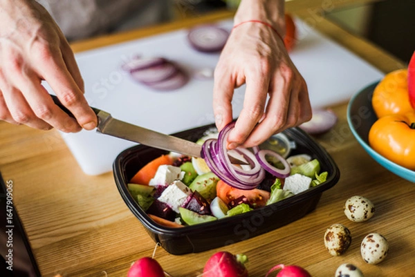Obraz Hands cutting onion and radish for fresh vegetable salad.