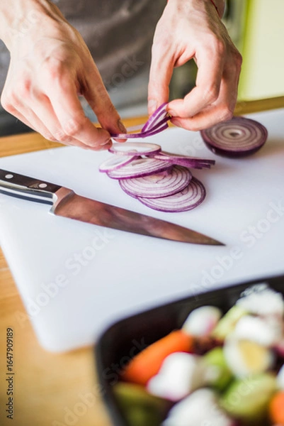 Obraz Hands cutting onion and radish for fresh vegetable salad.