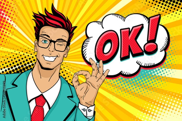Fototapeta Wow pop-art męskiej twarzy. Młody przystojny mężczyzna w okularach uśmiecha się, mruga i pokazuje ok znak i OK! dymek. Ilustracja wektorowa w stylu retro komiks. Tło wektor pop-artu. Plakat z zaproszeniem.