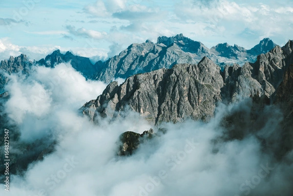 Fototapeta Dramatic View of Tre Cime di Lavaredo Peaks Shrouded in Clouds under Blue Sky