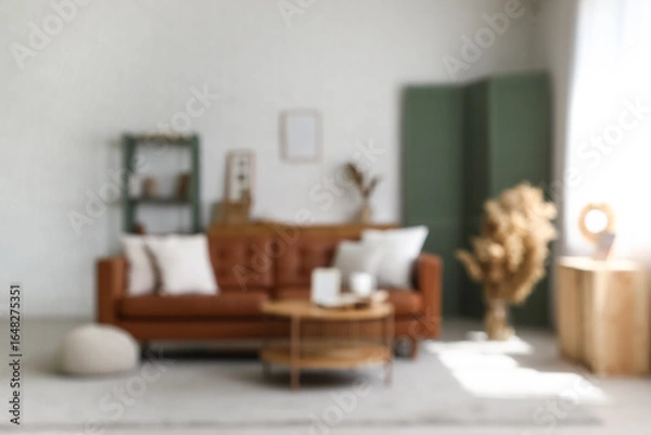 Fototapeta Blurred view of light living room with brown sofa, table and folding screen