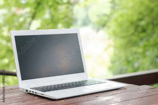 Obraz Stock photo :.Computer Laptop on wooden table with blur nature bokeh background, business technology concept